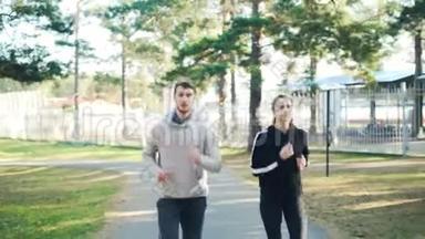 在秋天的一天，男生和女生穿着现代运动服一起在公园里跑步。 常<strong>青松</strong>